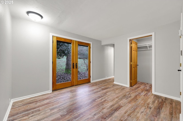 unfurnished bedroom with a closet, light hardwood / wood-style flooring, and french doors