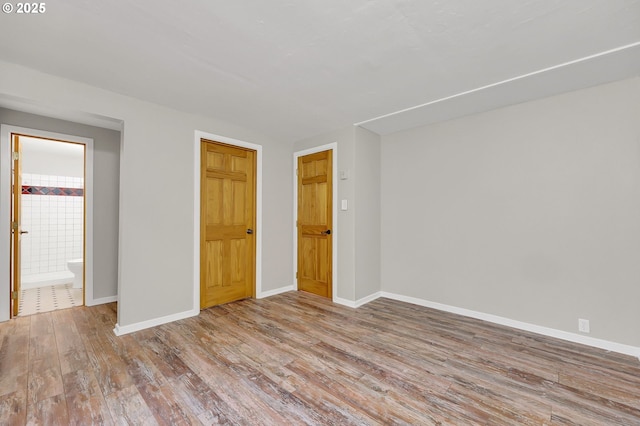 unfurnished bedroom with ensuite bathroom, light hardwood / wood-style flooring, and a closet