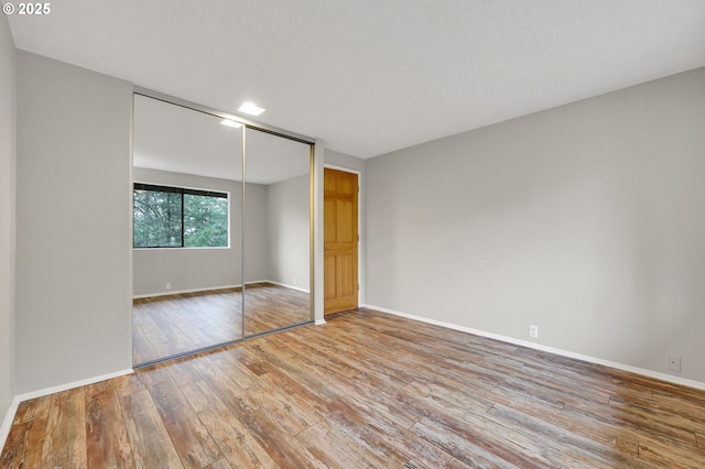 unfurnished bedroom with light wood-type flooring and a closet