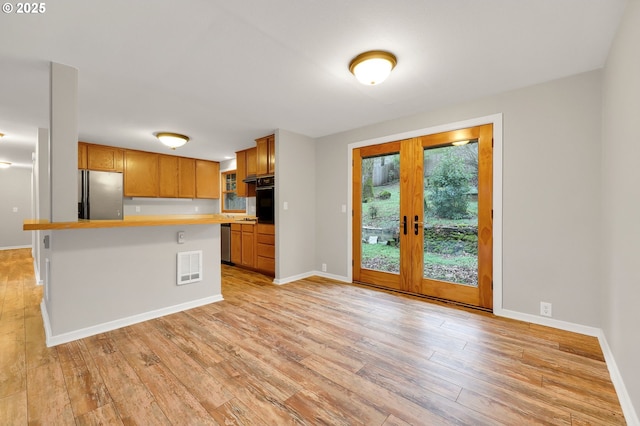 kitchen with light hardwood / wood-style floors, appliances with stainless steel finishes, a kitchen breakfast bar, french doors, and a kitchen island