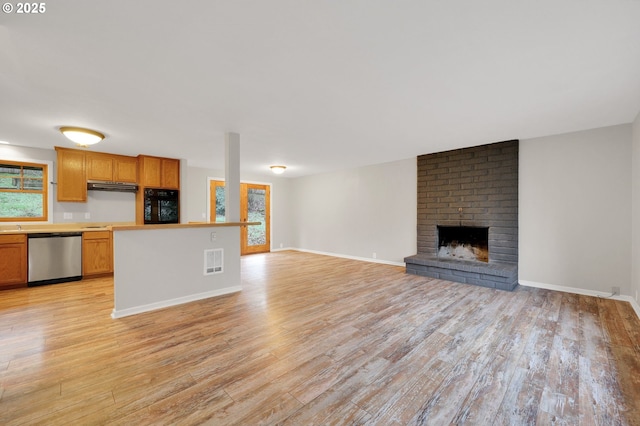 unfurnished living room with a brick fireplace and light hardwood / wood-style floors