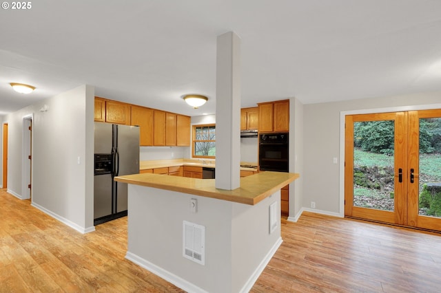 kitchen featuring french doors, stainless steel fridge, oven, and light hardwood / wood-style floors