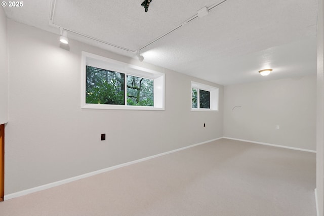 unfurnished room with a textured ceiling, carpet flooring, and rail lighting