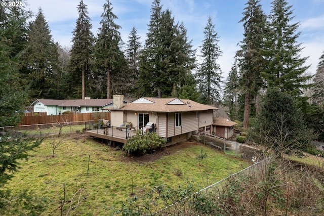 back of house with a fenced backyard, a chimney, a lawn, and a wooden deck