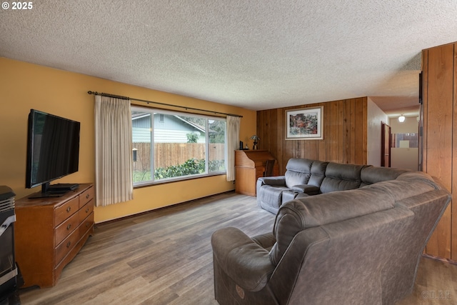 living room with a textured ceiling, wooden walls, and wood finished floors