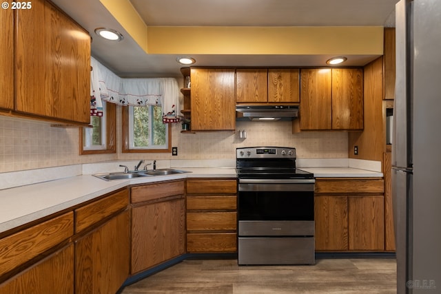 kitchen featuring under cabinet range hood, appliances with stainless steel finishes, light countertops, and brown cabinetry