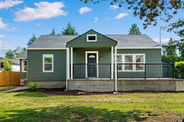 bungalow-style house with covered porch, roof with shingles, fence, and a front lawn