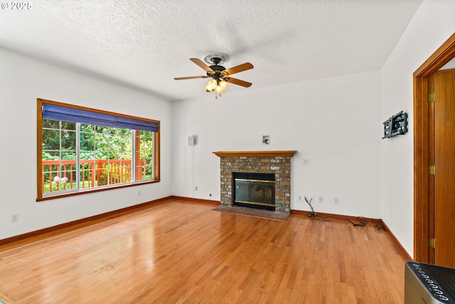 4060 Hampshire Ln, Eugene, OR 97404 - unfurnished living room featuring light wood-type flooring, a textured ceiling, a fireplace, and a ceiling fan