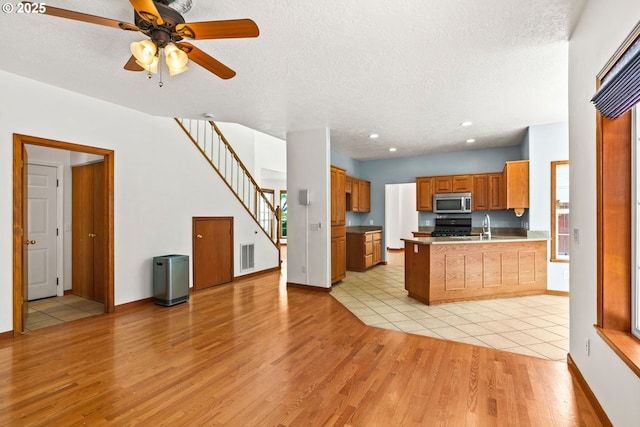 4060 Hampshire Ln, Eugene, OR 97404 - kitchen with stainless steel microwave, light wood-style floors, open floor plan, a peninsula, and a textured ceiling