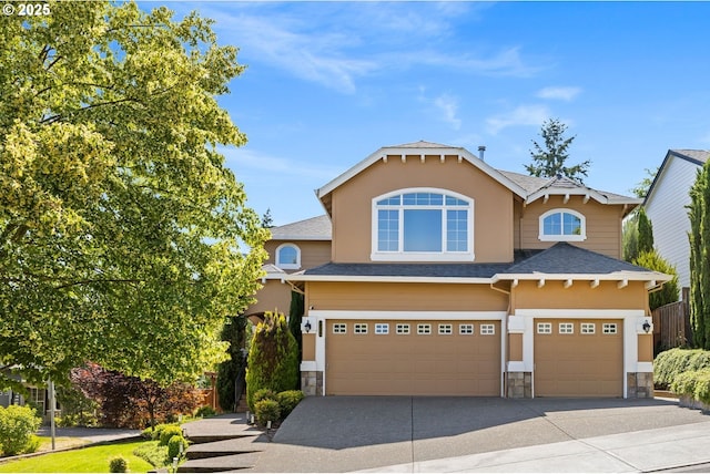 15655 SW Greenfield Dr, Portland, OR 97224 - view of front of home with stone siding, an attached garage, driveway, roof with shingles, and stucco siding