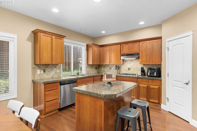 15655 SW Greenfield Dr, Portland, OR 97224 - kitchen featuring stainless steel appliances, under cabinet range hood, wood finished floors, a kitchen bar, and recessed lighting