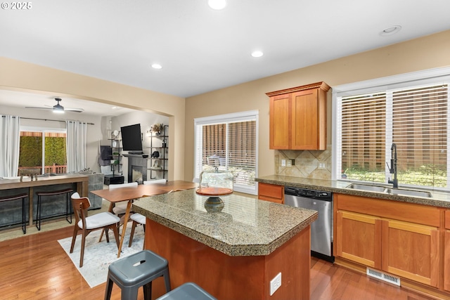 15655 SW Greenfield Dr, Portland, OR 97224 - kitchen featuring dishwasher, tile counters, a kitchen island, a breakfast bar area, and wood finished floors