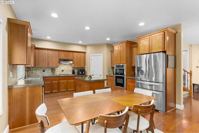 15655 SW Greenfield Dr, Portland, OR 97224 - kitchen with appliances with stainless steel finishes, under cabinet range hood, a center island, light wood-type flooring, and recessed lighting