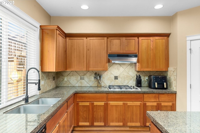 15655 SW Greenfield Dr, Portland, OR 97224 - kitchen with under cabinet range hood, stainless steel gas cooktop, brown cabinets, and decorative backsplash