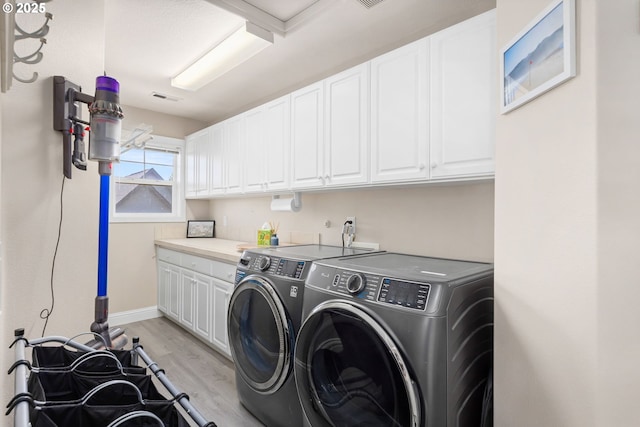 15655 SW Greenfield Dr, Portland, OR 97224 - laundry area featuring washing machine and dryer, cabinet space, and light wood finished floors