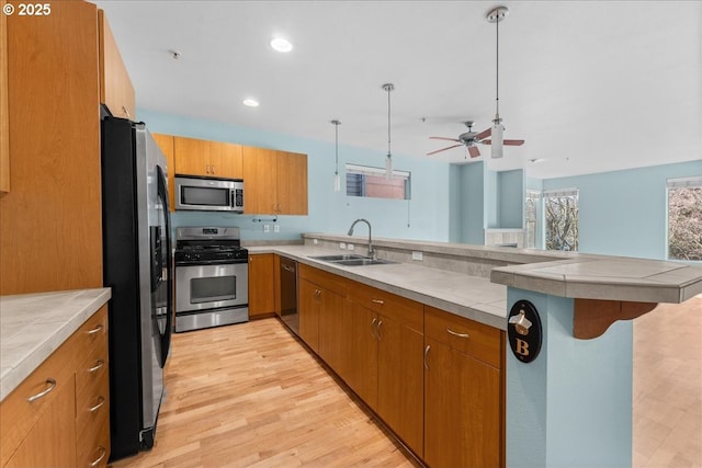 kitchen with pendant lighting, a kitchen bar, stainless steel appliances, light hardwood / wood-style floors, and sink