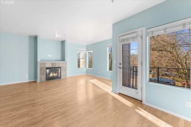 unfurnished living room featuring light hardwood / wood-style flooring and a tile fireplace