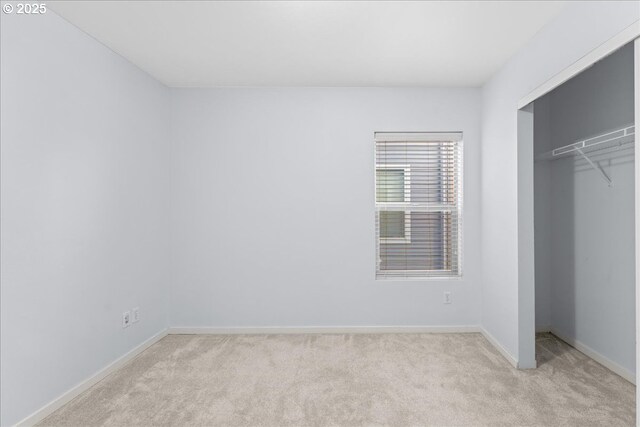 unfurnished bedroom featuring light colored carpet and a closet