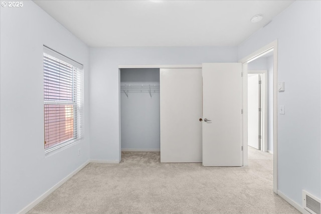 unfurnished bedroom with light colored carpet and a closet