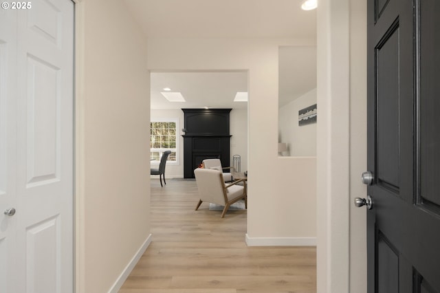 foyer featuring a large fireplace, baseboards, and light wood finished floors