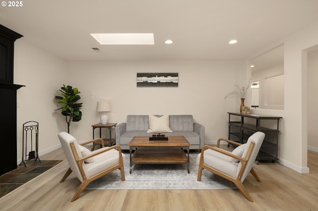 living room with a skylight, recessed lighting, light wood-style floors, and baseboards