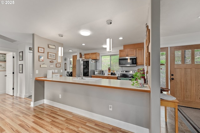 460 Huckleberry Mt Ln, Riddle, OR 97469 - kitchen with stainless steel appliances, a peninsula, hanging light fixtures, light wood-style floors, and recessed lighting