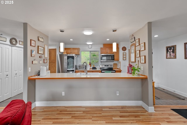 460 Huckleberry Mt Ln, Riddle, OR 97469 - kitchen with appliances with stainless steel finishes, a peninsula, a sink, light wood-type flooring, and hanging light fixtures