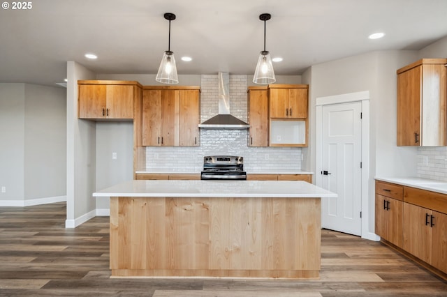 kitchen featuring pendant lighting, hardwood / wood-style flooring, a center island, electric range, and wall chimney exhaust hood