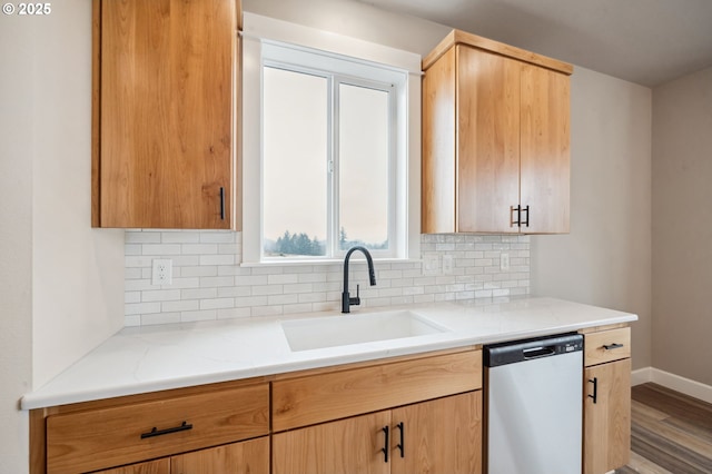 kitchen featuring sink, light stone counters, wood-type flooring, decorative backsplash, and stainless steel dishwasher