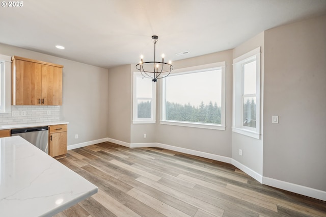 kitchen featuring a chandelier, light wood-type flooring, stainless steel dishwasher, pendant lighting, and decorative backsplash