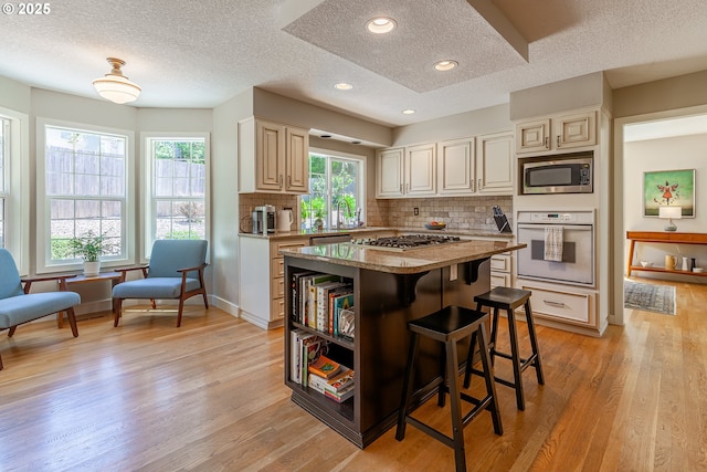 kitchen with tasteful backsplash, a center island, light wood-style flooring, a kitchen breakfast bar, and stainless steel appliances