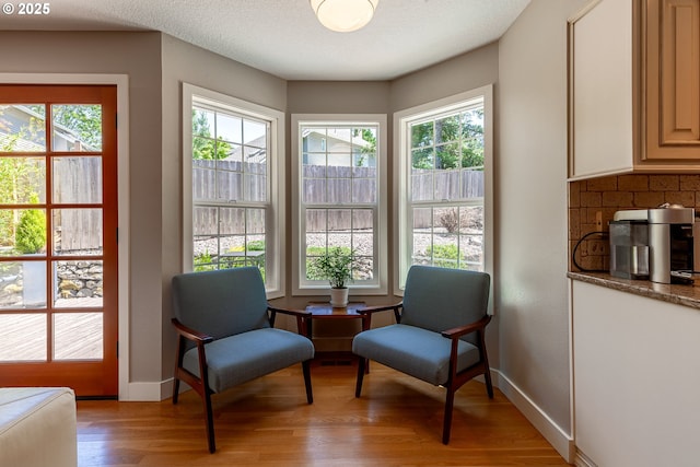 sitting room featuring baseboards, a textured ceiling, and light wood-style flooring