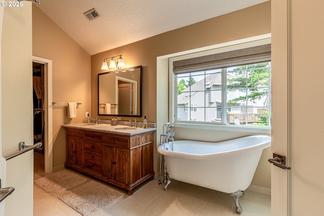 full bathroom with visible vents, a freestanding tub, a sink, vaulted ceiling, and tile patterned floors