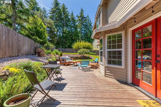 wooden terrace with an outdoor living space and a fenced backyard