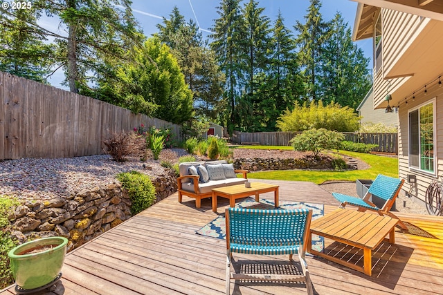 deck featuring a shed, outdoor lounge area, a fenced backyard, and an outdoor structure