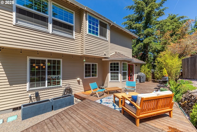 deck with an outdoor living space, a grill, and fence