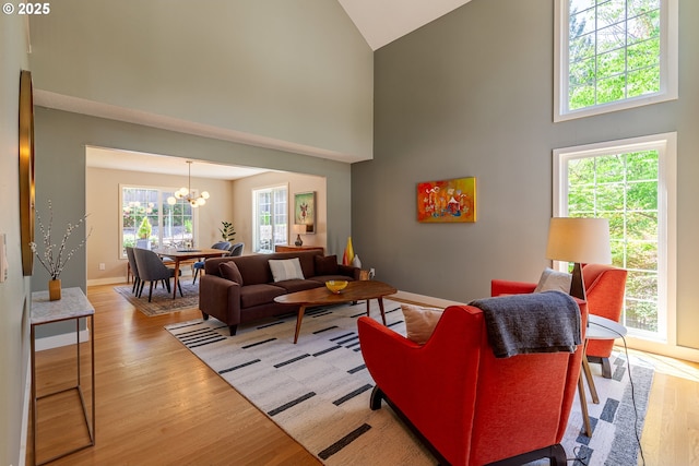 living room featuring light wood finished floors, high vaulted ceiling, baseboards, and an inviting chandelier