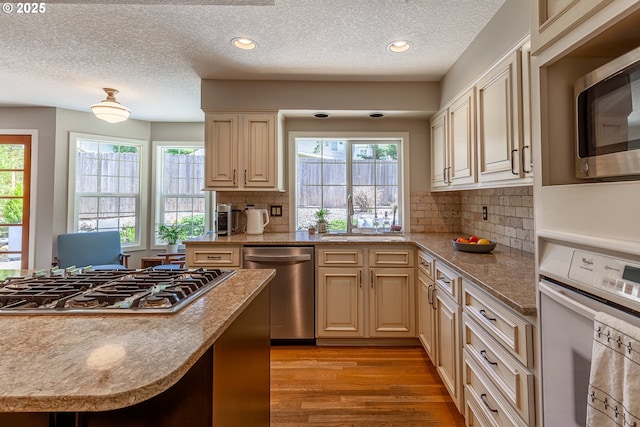 kitchen with a sink, tasteful backsplash, recessed lighting, appliances with stainless steel finishes, and light wood finished floors