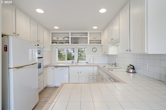kitchen with open shelves, a sink, white appliances, tile countertops, and tasteful backsplash