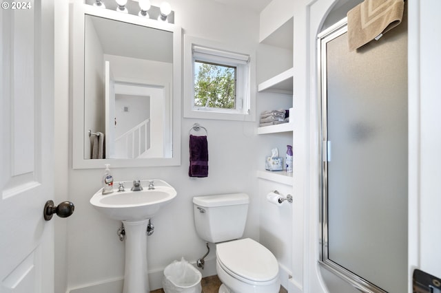 full bath featuring a sink, a shower with shower door, and toilet