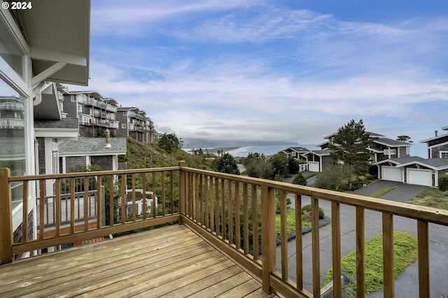 wooden terrace featuring a detached garage and a residential view