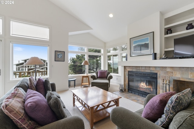 living area with a tiled fireplace, recessed lighting, built in features, and high vaulted ceiling