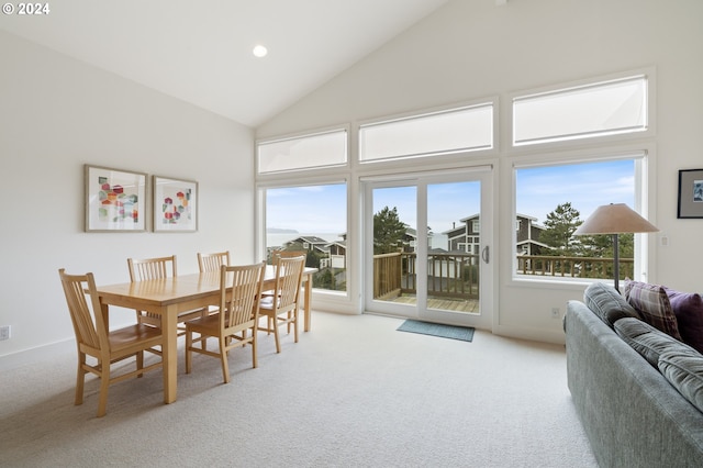 dining area with carpet floors and high vaulted ceiling
