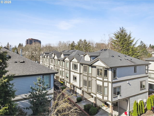 exterior space featuring a shingled roof and a residential view