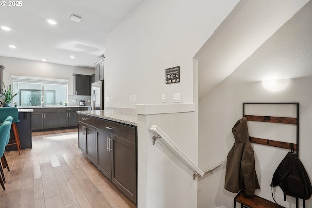 8887 SW Elena Ln, Portland, OR 97223 - kitchen with stainless steel refrigerator, light wood-type flooring, recessed lighting, and light stone counters