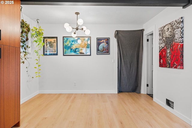 spare room with an inviting chandelier and light hardwood / wood-style flooring