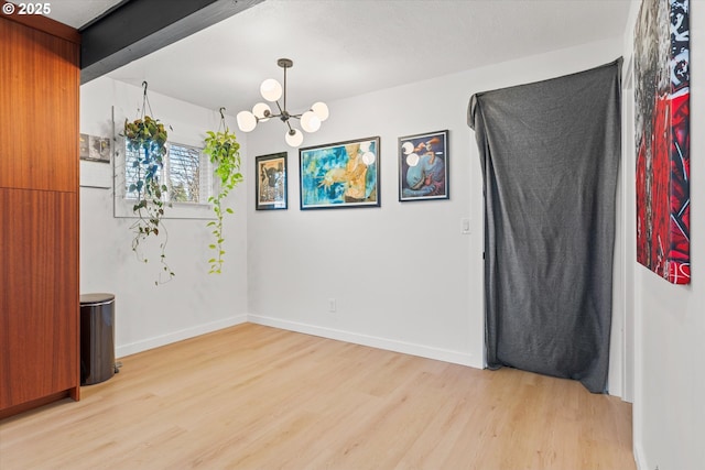 unfurnished room with a chandelier and light wood-type flooring