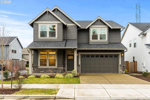 craftsman-style house with a garage, stone siding, fence, and concrete driveway