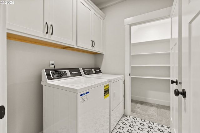 washroom featuring washing machine and clothes dryer, cabinet space, and baseboards