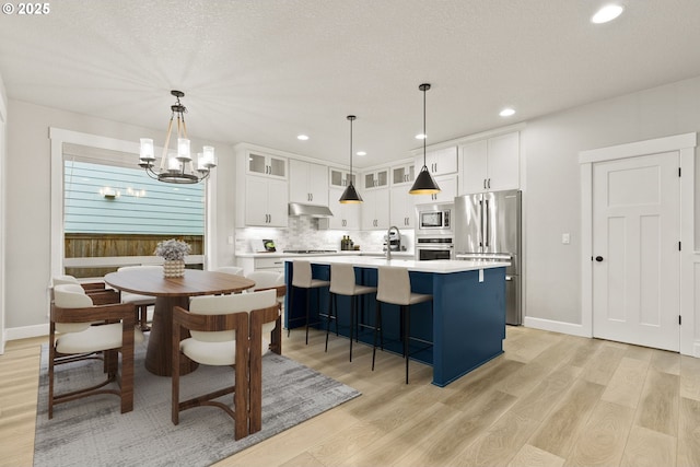 kitchen featuring stainless steel appliances, light countertops, glass insert cabinets, and white cabinetry